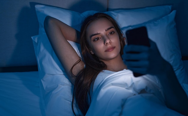 Jeune femme utilisant un téléphone portable tard dans la nuit