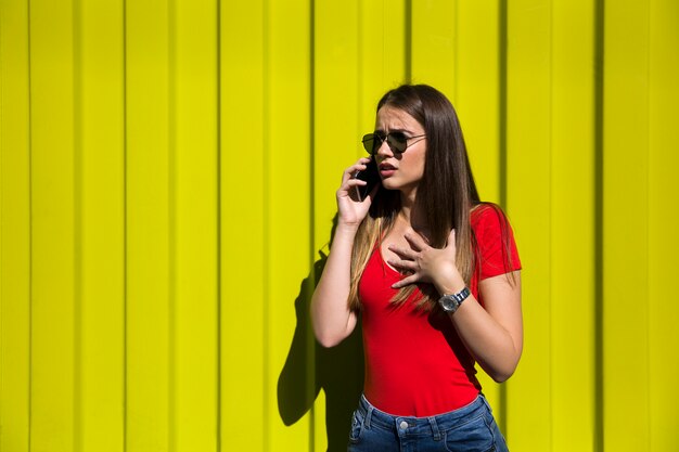 Jeune femme, utilisation, téléphone portable, par, les, mur jaune