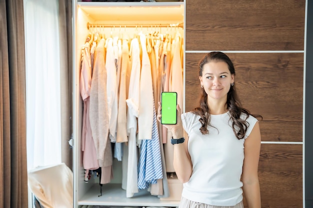 Photo une jeune femme utilise une application pour smartphone pour vendre de vieux vêtements indésirables dans l'application chroma écran vert