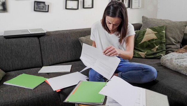 Photo une jeune femme utilise un ordinateur portable alors qu'elle est assise sur le canapé à la maison