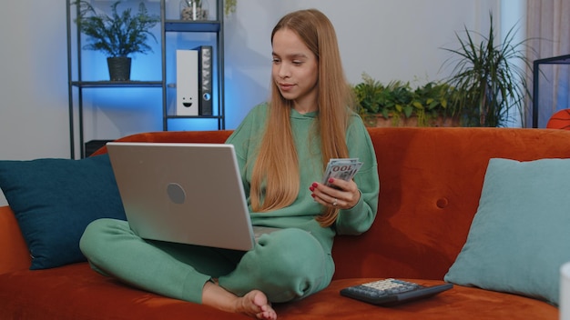 Photo une jeune femme utilise un ordinateur portable alors qu'elle est assise sur le canapé à la maison