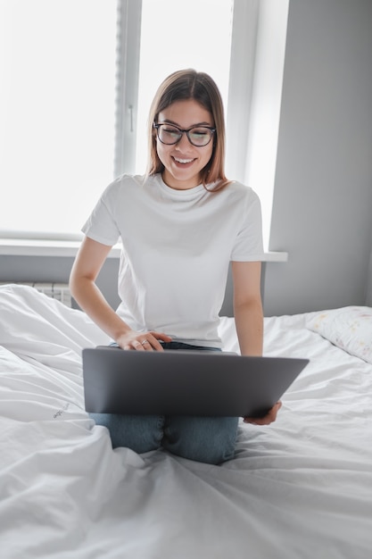 Jeune femme utilise un ordinateur portable à la maison sur le lit