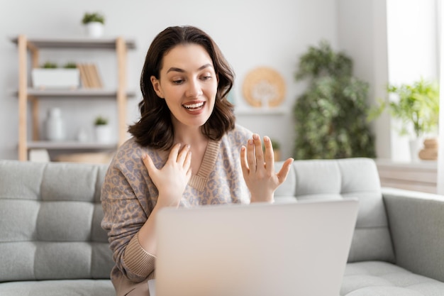 Jeune femme utilise un ordinateur portable pour une conversation à distance avec des amis