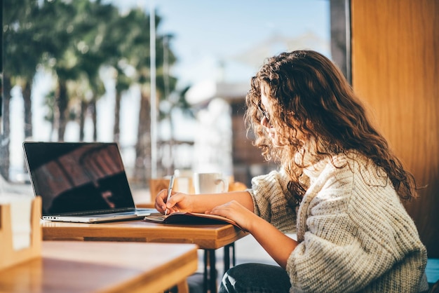 Une jeune femme utilise un ordinateur portable à la table.