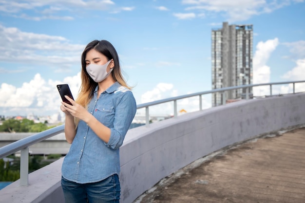 Une jeune femme utilise son téléphone alors qu'elle se tient sur la balustrade.