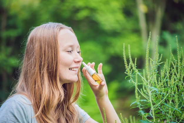 Une jeune femme utilise un spray contre une allergie à cause d'une allergie à l'ambroisie