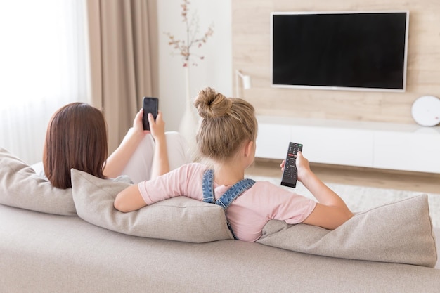 Une jeune femme utilise un téléphone portable alors qu'elle est allongée sur le lit à la maison.