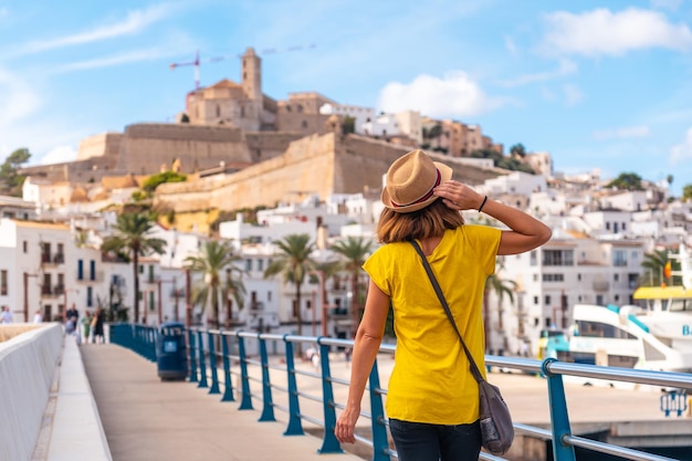 Photo une jeune femme en vacances de printemps dans la ville d'ibiza à côté du phare des îles baléares