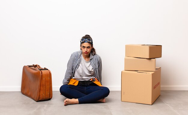 Jeune femme avec valise et boîtes en carton. Concept en mouvement.