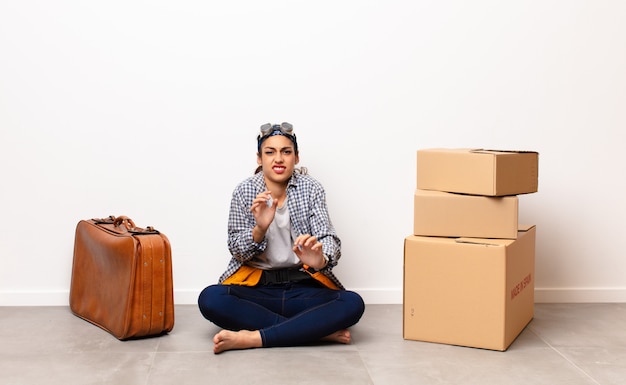 Jeune femme avec valise et boîtes en carton. Concept en mouvement.