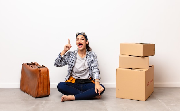 Jeune femme avec valise et boîtes en carton. Concept en mouvement.