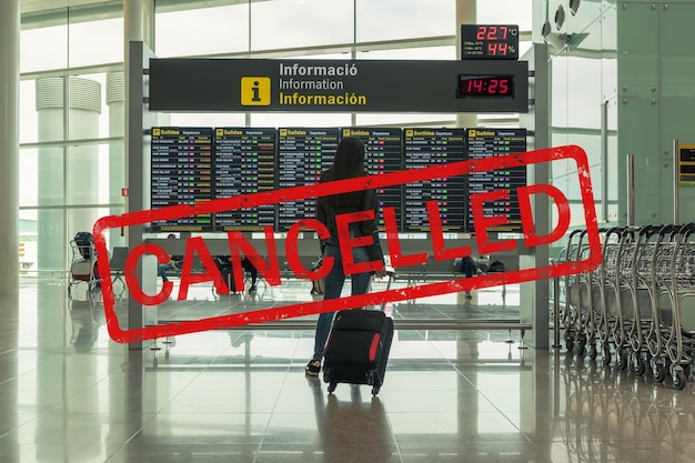 Jeune femme avec valise dans le hall des départs à l'aéroport.