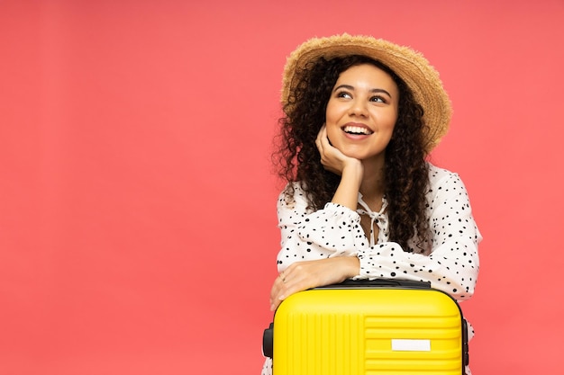 Jeune femme avec valise sur fond rose