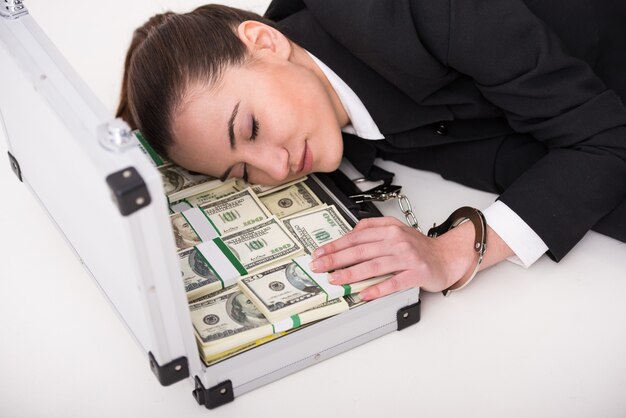 Jeune femme avec une valise pleine d'argent et de menottes.