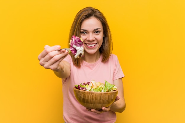 Jeune femme végétalienne mangeant une salade fraîche et délicieuse.