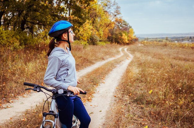 Jeune femme à vélo dans le champ d&#39;automne