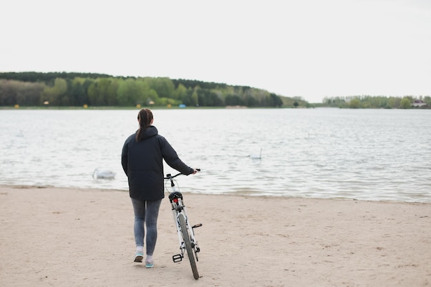 Une jeune femme avec un vélo sur le lac