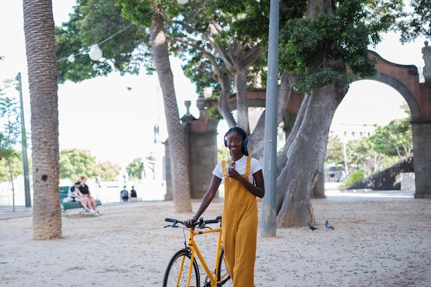 Une jeune femme à vélo à travers la ville mangeant une crème glacée Style de vie conceptuel en plein air