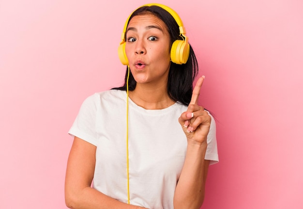 Jeune femme vénézuélienne écoutant de la musique isolée sur fond rose ayant une excellente idée de concept de créativité