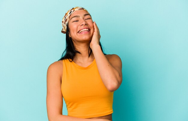Jeune femme vénézuélienne isolée sur fond bleu riant émotion heureuse, insouciante et naturelle.
