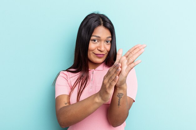 Jeune femme vénézuélienne isolée sur fond bleu se sentant énergique et confortable, se frottant les mains en toute confiance.