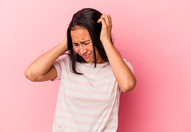 Jeune femme vénézuélienne isolée sur fond rose couvrant les oreilles avec les mains