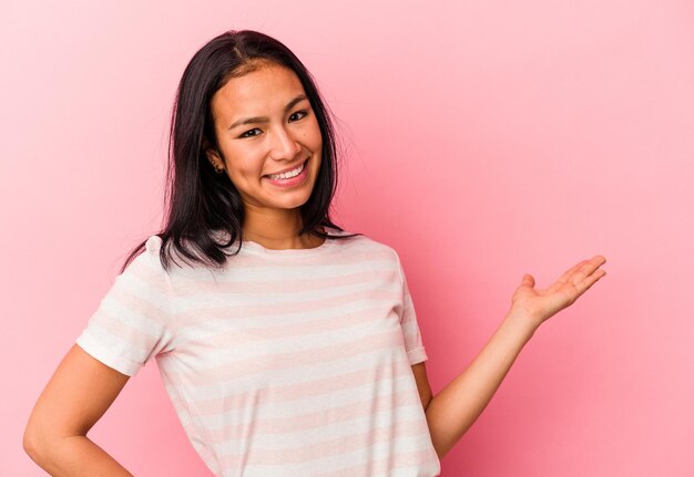 Jeune femme vénézuélienne isolée sur fond rose montrant une expression bienvenue