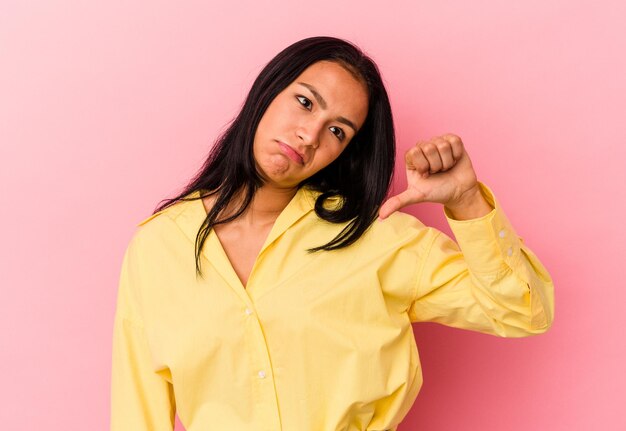 Jeune femme vénézuélienne isolée sur fond rose montrant un geste d'aversion vers le bas Concept de désaccord