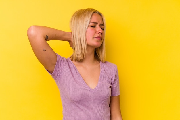 Jeune femme vénézuélienne isolée sur mur jaune ayant une douleur au cou due au stress, en massant et en la touchant avec la main