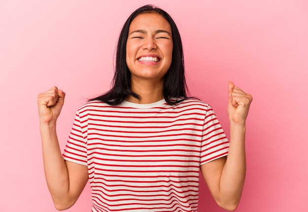 Jeune femme vénézuélienne isolée sur un mur rose célébrant une victoire, une passion et un enthousiasme, une expression heureuse.