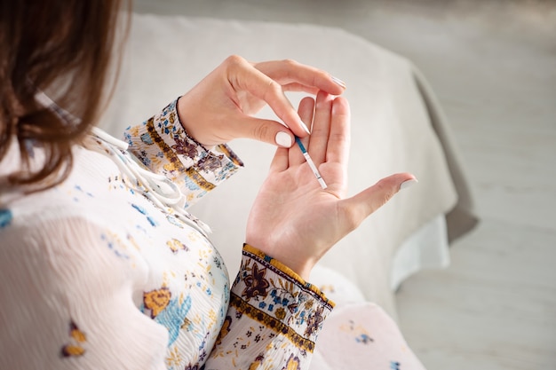 Jeune femme vérifiant le kit de test de grossesse dans la chambre