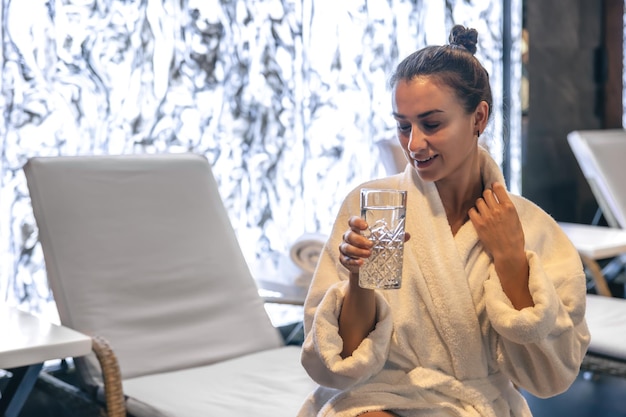 Une Jeune Femme Avec Un Verre D'eau Après Le Sauna Se Repose