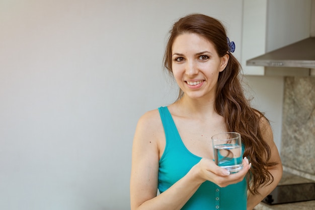 Une jeune femme avec un verre d'eau dans les mains