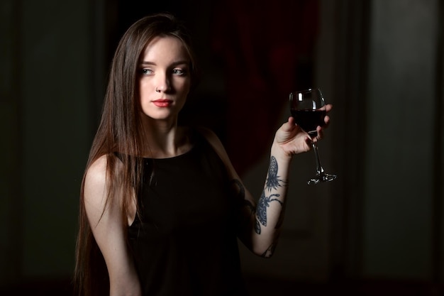 Jeune femme avec un verre de vin rouge dans la chambre