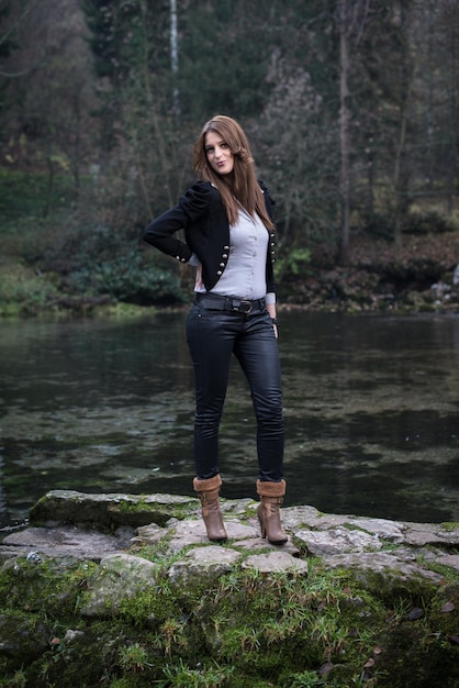 jeune femme en veste debout et posant au bord du lac