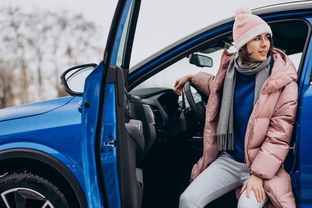 Jeune femme en veste d'hiver assise dans sa nouvelle voiture