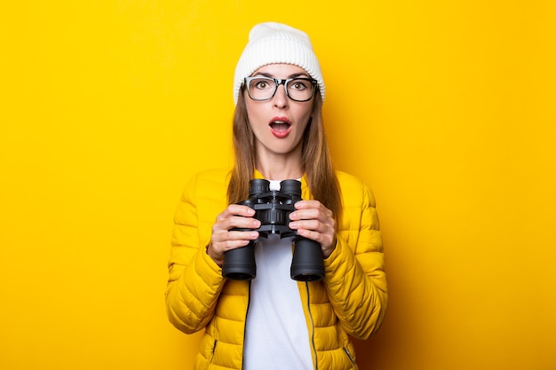 Jeune femme en veste jaune tenant des jumelles