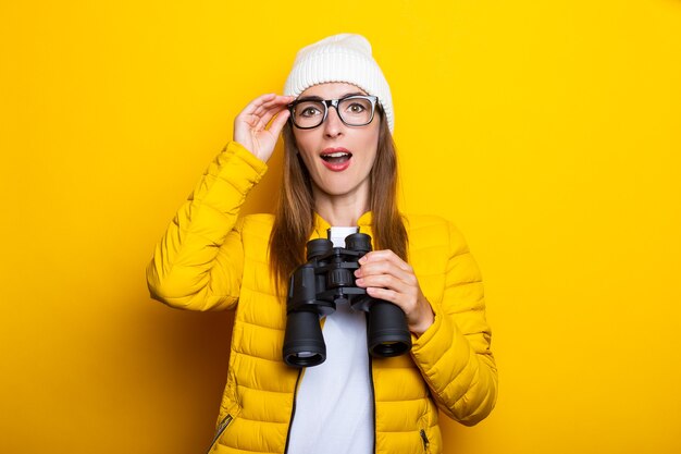 Jeune femme en veste jaune tenant des jumelles