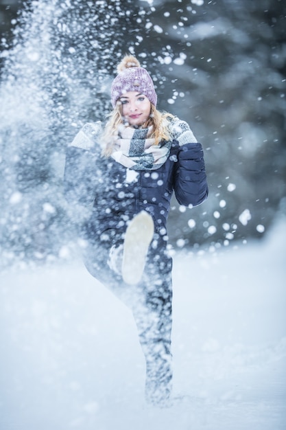 Jeune femme en vêtements chauds s'amuse hors de la neige.