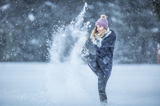 Jeune femme en vêtements chauds s'amuse hors de la neige.