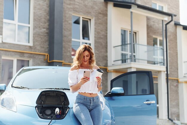 Jeune femme en vêtements décontractés avec son électromobile à l'extérieur pendant la journée