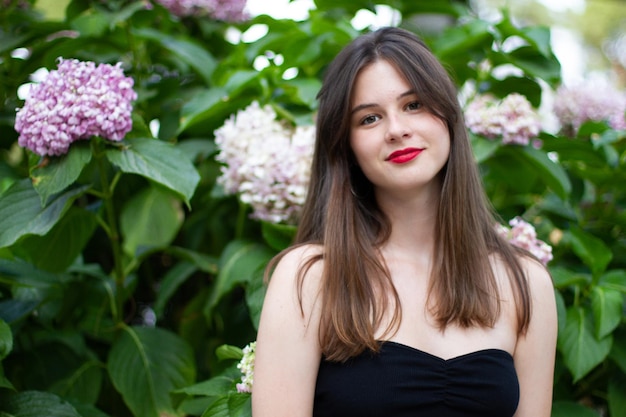 Jeune femme avec des vêtements élégants posant dans un parc paradisiaque