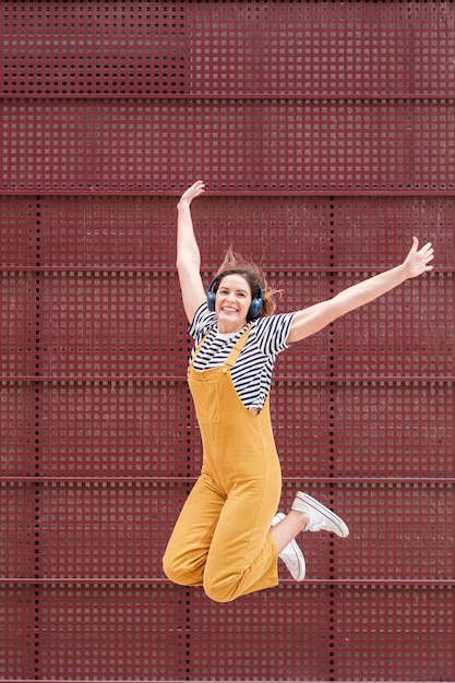 Jeune femme en vêtements jaunes sautant et heureux sur un fond rouge dans la ville bonheur de style de mode de vie Concept