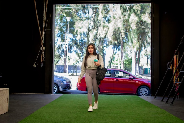 Photo une jeune femme en vêtements de sport entrant dans la salle de sport avec son équipement d'entraînement concept de publicité sportive