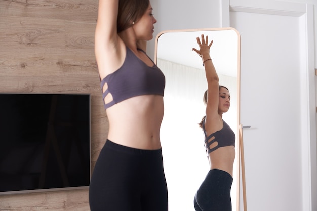 Jeune femme en vêtements de sport faisant du yoga tout en se relaxant à la maison