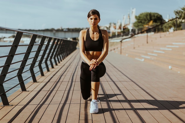 Jeune femme en vêtements de sport faisant de l'exercice sur une promenade fluviale