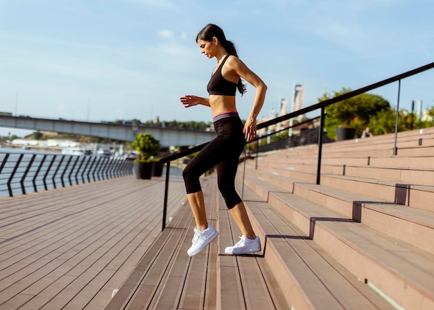 Jeune femme en vêtements de sport faisant de l'exercice sur une promenade fluviale