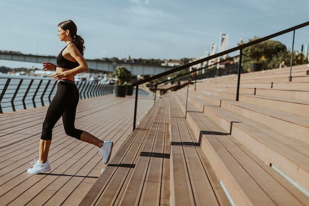 Jeune femme en vêtements de sport faisant de l'exercice sur une promenade fluviale