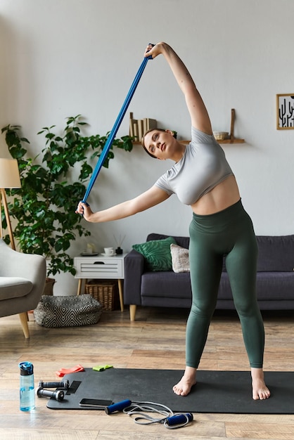 Une jeune femme en vêtements de sport s'entraîne à la maison tout en s'étirant au soleil.