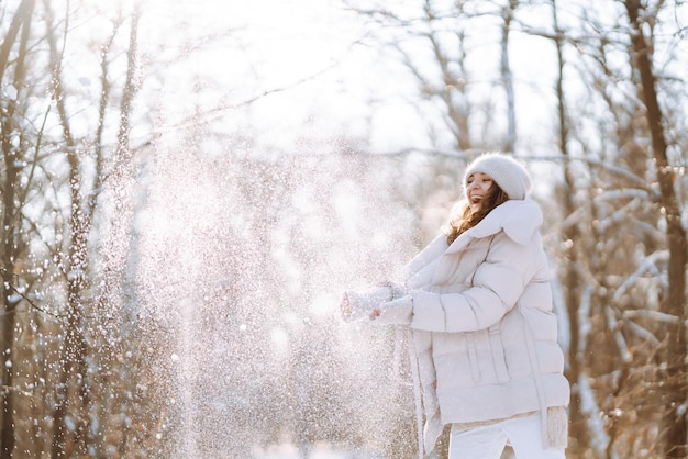 Jeune femme en vêtements de style hiver marchant dans le parc enneigé Vacances de mode d'hiver